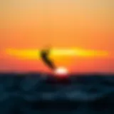 A kitesurfer riding the waves against a stunning sunset backdrop