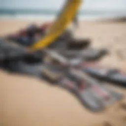 An assortment of used kiteboarding gear displayed on a sandy beach